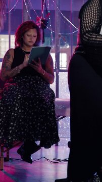 Client, tablet and woman in tattoo parlor with internet for ink design, choice or browsing for inspiration. Technology, scroll and person at shop with art blog, style decision and neon lights