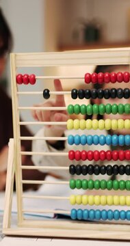 Abacus, counting and hand of girl in home with mother for child development, homework or learning. Education, maths and woman teaching daughter at counter in apartment for knowledge or numeracy
