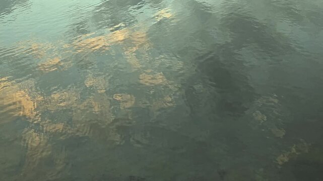 footage of Wavy Water Surface Reflecting Golden Sky And Clouds