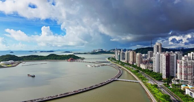 Aerial view of the coastal city with a bridge and modern residential buildings along the bay in Zhuhai, China