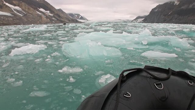 A small boat navigates through a stunning field of brilliant ice floes and bergs in the Arctic Ocean.