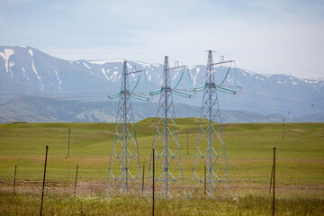 Fototapeta premium Electric pylons stretch across a green, open field