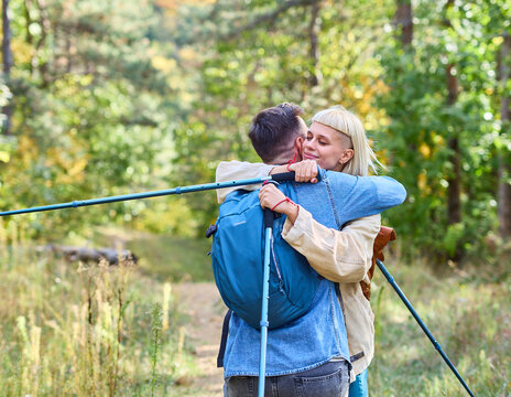 Hiking couple, young man and woman enjoys nature with trekking poles in a lush forest during a sunny day