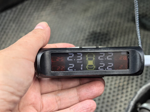 Hand holding TPMS tire pressure monitoring system display inside car