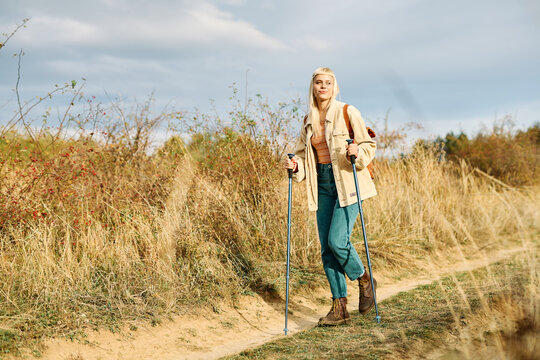 Hiking woman enjoys nature with trekking poles in a lush forest during a sunny day