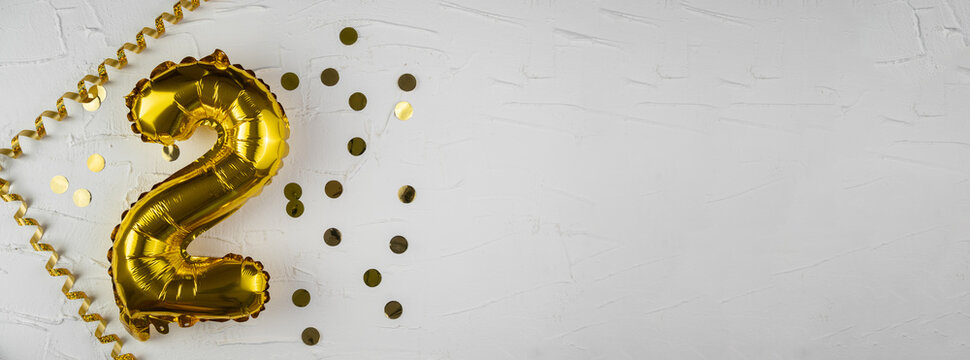 Yellow Gold foil balloon number two on a concrete background. Birthday card with lettering 2. Anniversary concept. For anniversary, birthday, wedding event, new year celebration. Banner