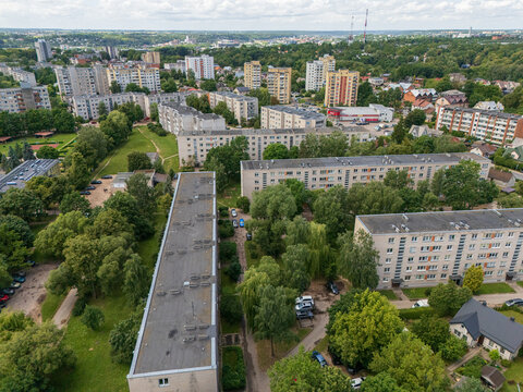 Aerial view of Soviet-era block apartment buildings in Lithuania surrounded by green trees and summer vegetation, urban residential microdistrict and eastern european architecture concept