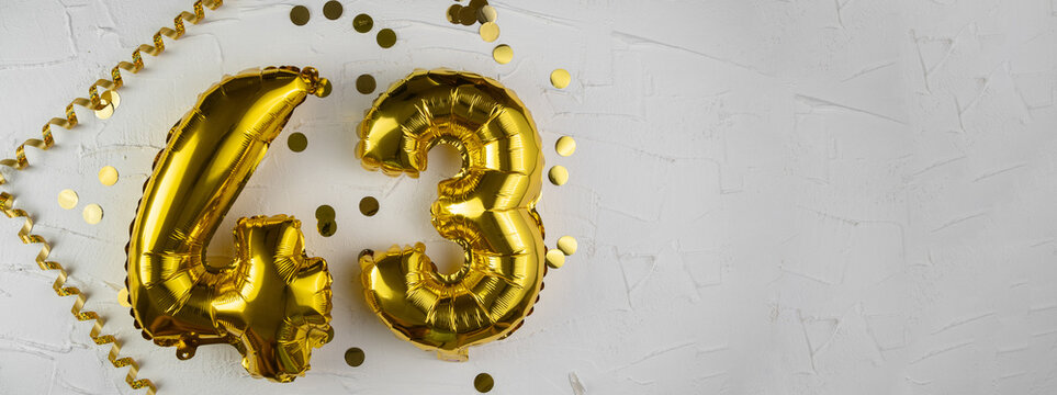 Yellow Gold foil balloon number forty-three on a concrete background. Birthday card with lettering 43. Anniversary concept. For anniversary, birthday, wedding event, new year celebration.