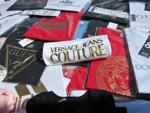 Counterfeit luxury brand t-shirts for sale at street market stall