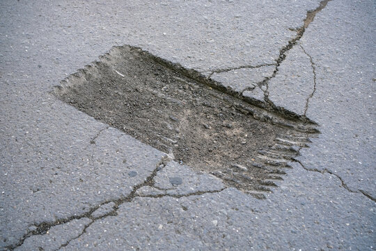 asphalt road prepared for pothole repair. cut-out section of pavement before laying new asphalt. road maintenance, infrastructure, resurfacing, construction and repair work.