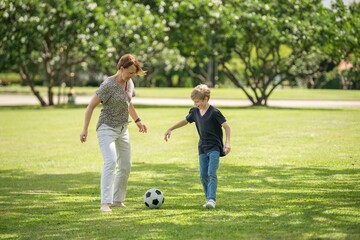 Fototapeta premium grandmother and grandson bonding joyful family moment playing soccer together. Happiness grandparent and childhood on weekend with football outdoor activity emotional connection