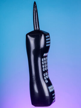 Close-up of an inflatable retro black mobile phone toy on a purple background, highlighting its vintage design and vibrant colors