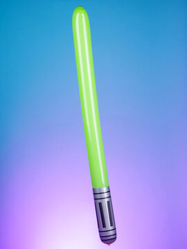 Close-up of an inflatable laser sword toy on a purple background, showcasing its bright colors and futuristic design