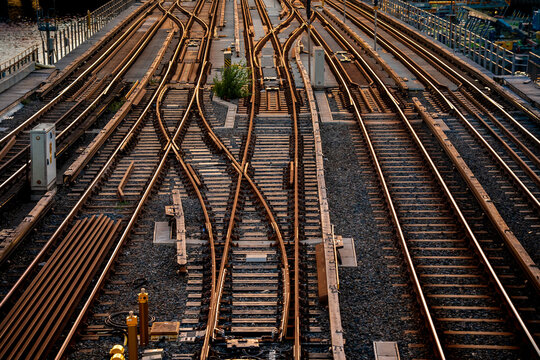 railway tracks and junction with switches and different paths leading into the distance in warm sunset light