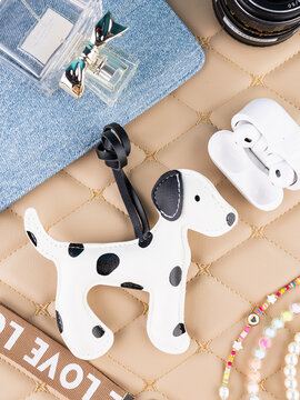 Close-up of a leather Dalmatian-shaped keychain on a beautiful table with women&rsquo;s accessories. Elegant and charming accessory