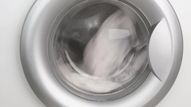 A hand opens the door of the washing machine.
