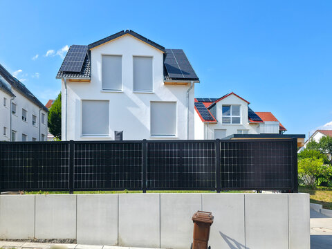 germany, modern house with rooftop photovoltaic system and solar garden fence under beautiful summer blue sky celebrating innovative sustainable architecture