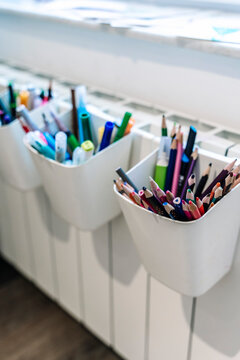 Organized colorful pencils and markers in white holders.
