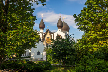 Moscow, Russia, Marfo-Mariinsky Convent. White orthodox church with dark onion domes and golden crosses framed by dense green trees in summer, © elenarostunova