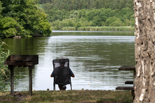 p&ecirc;cheur assis relax vu de dos &agrave; l'&eacute;tang