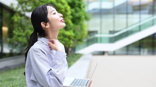 オフィス街でノートパソコンを使って仕事をする30代の日本人ビジネスパーソンの女性