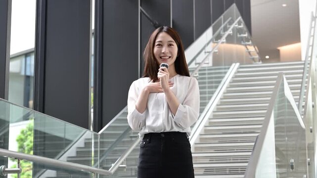 ピンマイクを持ってプレゼンテーションをする20代の日本人女性