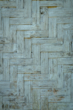 Close-up of woven bamboo wall texture featuring an interlocking geometric pattern, showcasing natural material, rustic craftsmanship, and decorative surface background.