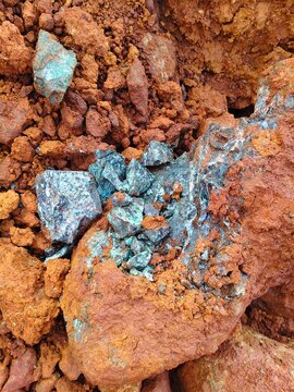 Fragmented high-grade nickel ore chunks showing dark green garnierite silicates mixed with heavy reddish laterite clay at an open-pit mine