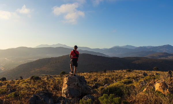 An 11-year-old boy with an arm brace stands on a rock, looking at mountain panorama in Crete. Inspiring travel of youth adventure, achieving goals, and overcoming physical injury during holidays
