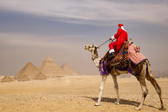 Rear view of Santa Claus on a decorated camel gazing across the sunlit Giza desert toward three ancient pyramids ideal for whimsical Christmas travel
