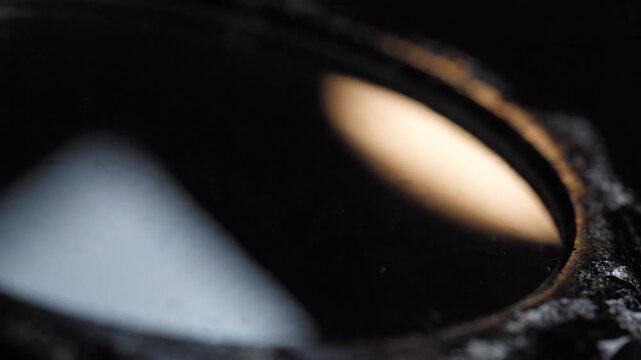 Macro of a polished black obsidian or scrying mirror with subtle light reflection, perfect for mystic or abstract themes