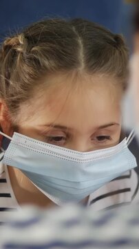 A girl with a striped shirt looks intently at a woman. The girl smiles softly, creating a moment of connection with the woman in the scene.