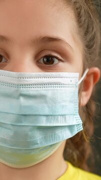A girl wears a protective mask that covers her mouth and nose. The girl has light brown hair and intense eyes, emphasizing the importance of safety and health awareness.