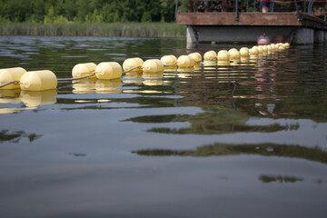Obraz premium Buoys marking the area of ​​a supervised swimming zone. A lakeside swimming area in summer. 