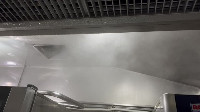 Steam generated from industrial cooking operations rising toward an exhaust hood and forming condensation droplets. Example of moisture management, ventilation systems, and environmental conditions in