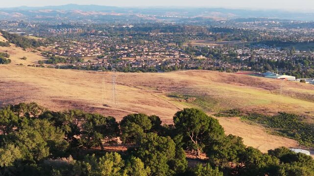 Telephoto helix move around a foreground oak tree at sunset, transmission towers crossing sun-dried golden grassland with the town of American Canyon layered in the distance.