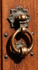 Obraz premium Antique bronze door knocker on weathered wood. Ring grip offers old world charm and detail. Rustic hardware adds texture and classic design element to entrance.