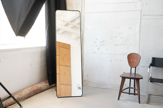 Full length mirror leaning against studio wall with chairs