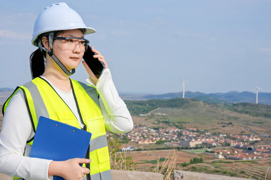 Female Engineer Talking On Phone At Outdoor Wind Farm Site