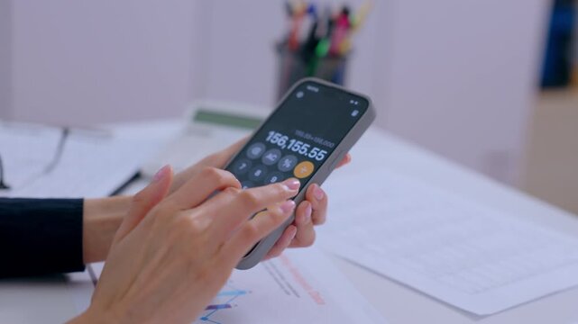 Smartphone hand using calculator app for finance document on office desk, business accounting touch screen calculation with paper chart laptop budget payment workflow