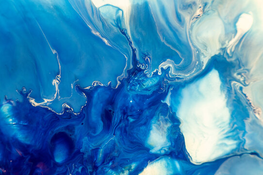 Swirls of blue colors mix together in an abstract design on a smooth surface