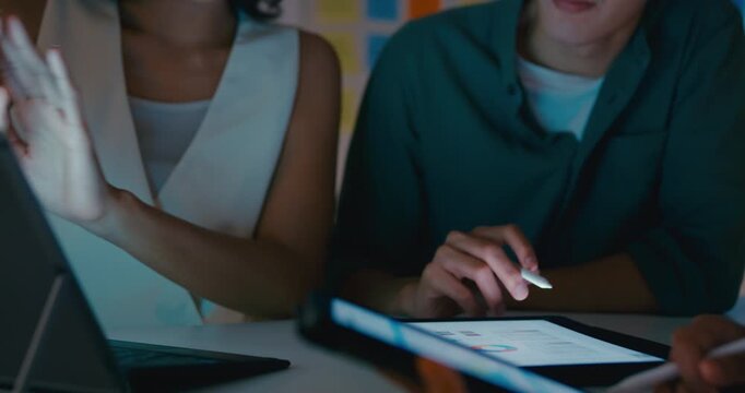 Closeup group Asian businesspeople work together discuss plan idea with data profit sale statistics in business meeting in office night. Financial generation z team brainstorm on e-Commerce project.
