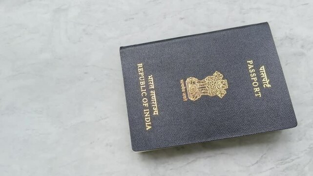 Close up od Indian international traveler person hand placing india passport on white table background with copy space. Citizenship or nationality id proof document. Immigration and migration concept.