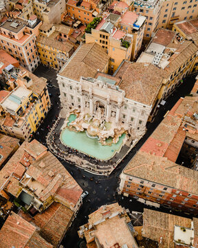 Aerial view of the Trevi Fountain in Rome, featuring its baroque facade and turquoise water basin surrounded by historic buildings and crowds of visitors. Rome, Lazio, Italy.
