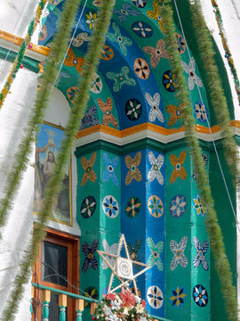 Decorated entrance of San Lorenzo Church in Zinacant&aacute;n, Chiapas, featuring vibrant floral motifs, traditional indigenous art, and colorful architectural details.