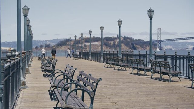 Pier Boardwalk Benches With Lamp Posts And View Of Suspension Bridge In San Francisco Bay