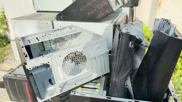 Abandoned computer cases sit in a messy pile outdoors. This forgotten hardware evokes feelings of neglect and nostalgia, highlighting the sad reality of electronic waste.