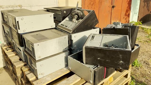 Discarded computer cases are piled on wooden pallets outdoors. This cluttered scene feels abandoned and forgotten, capturing the quiet sadness of obsolete technology waiting for a new purpose.