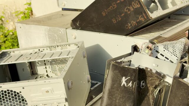 Abandoned computer cases lie piled in a messy outdoor heap. This forgotten hardware evokes a sad sense of neglect and the fleeting nature of technology.