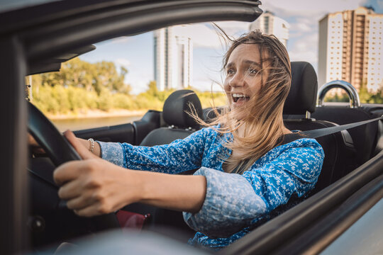 Scared young woman screaming while driving a convertible car. Driving phobia, beginner driver panic and nervous learning. Driving lesson stress.
